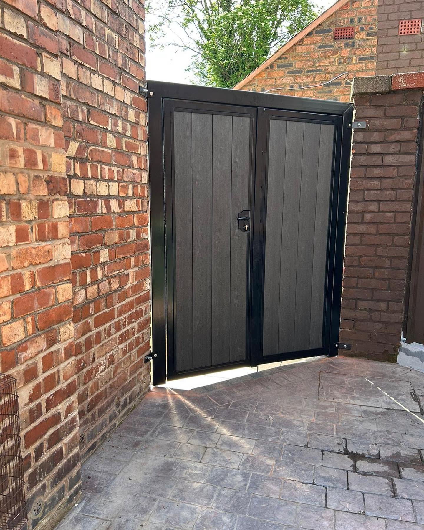 Black double side gates fitted between brick walls