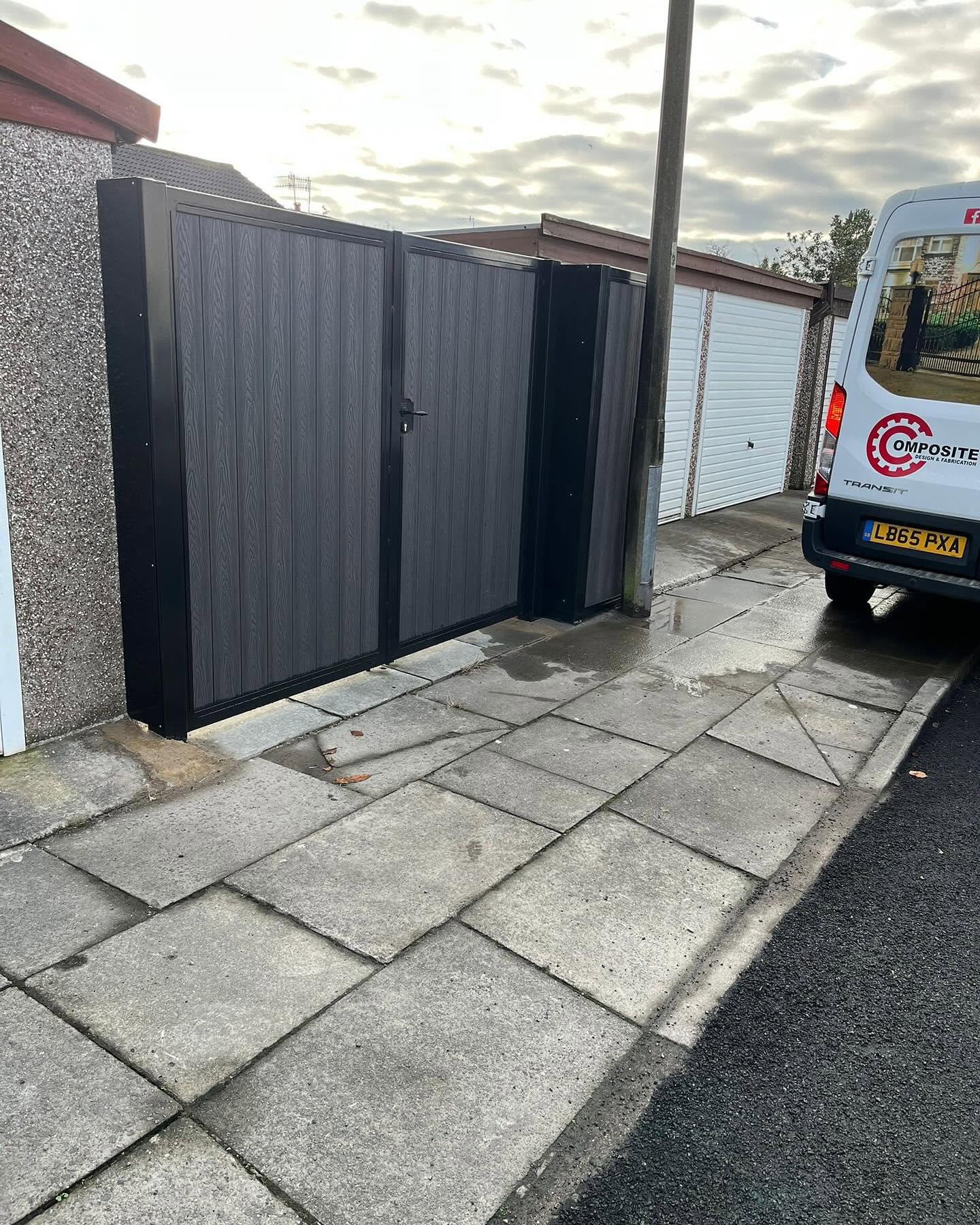 Black composite driveway gates installed at a side entrance